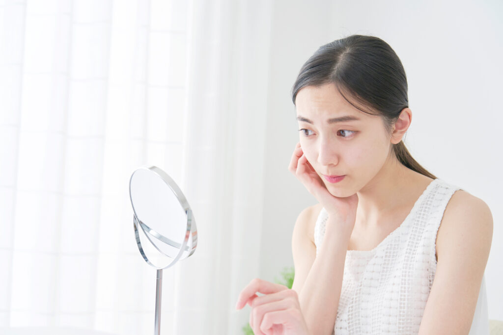 鏡を見て眉を気にする女性